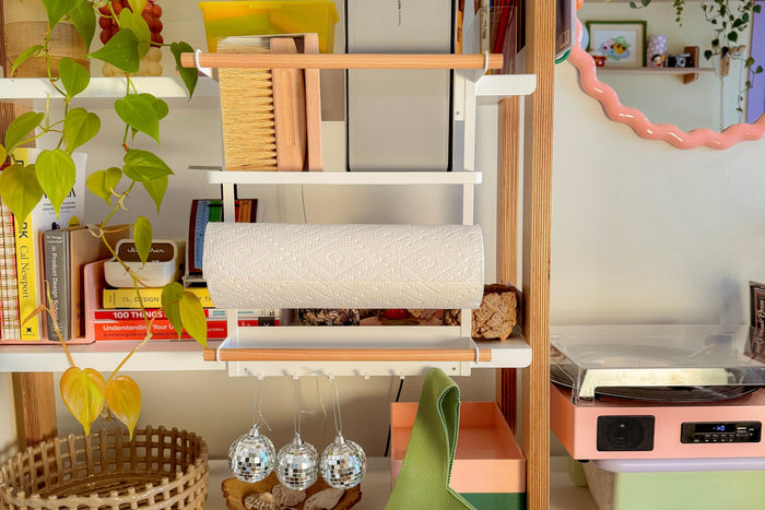 Magnetic Kitchen organizer attached to a bright open bookshelf with three disco balls hanging from the six hooks. The whole kitchen is bright and airy with greenery, mirrors, and a natural brush. 