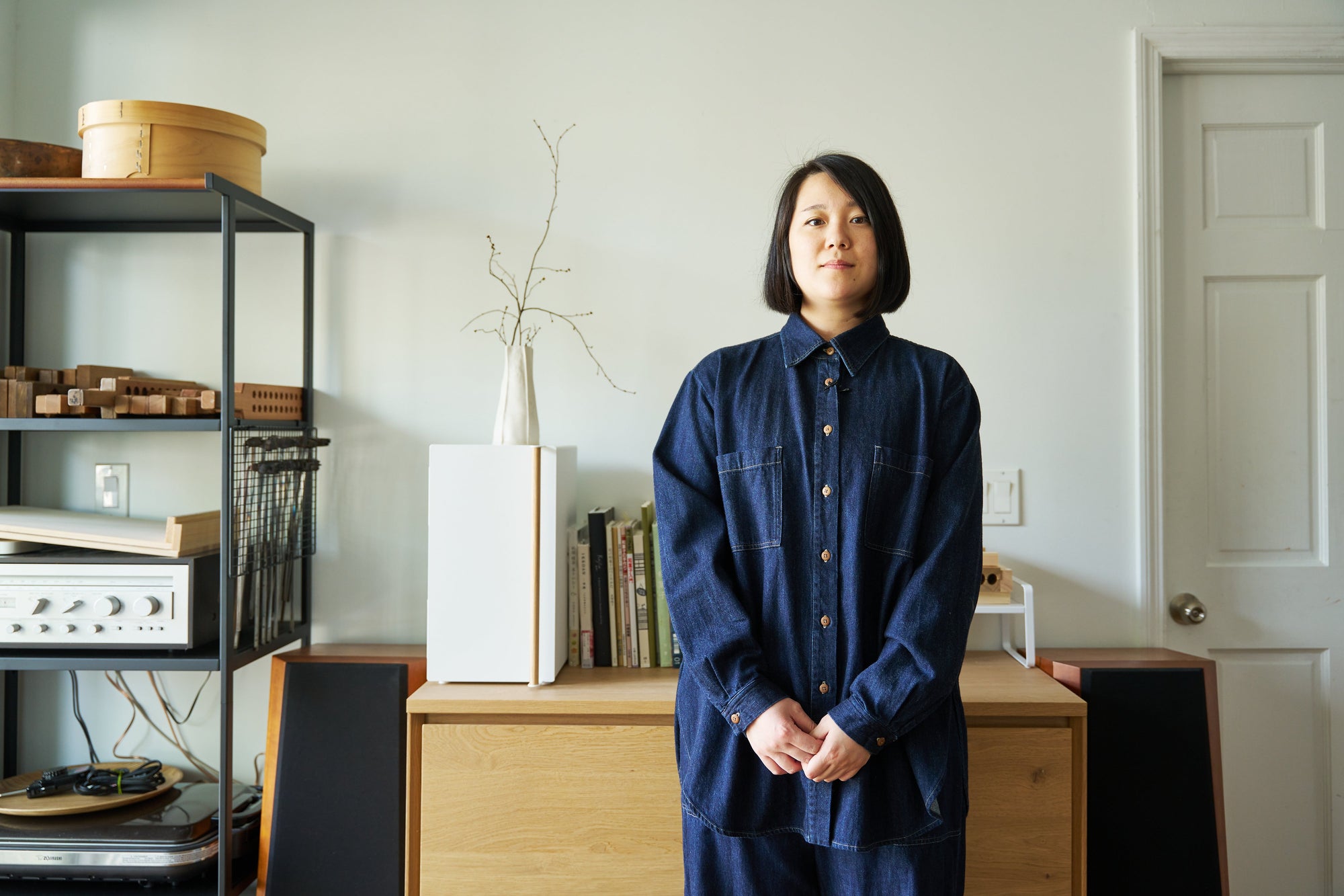 Phoebe Ogawa, NYC-based wagashi artist, stands in her studio in front of Yamazaki Home bread box, shelf riser, and three-tier storage rack. 
