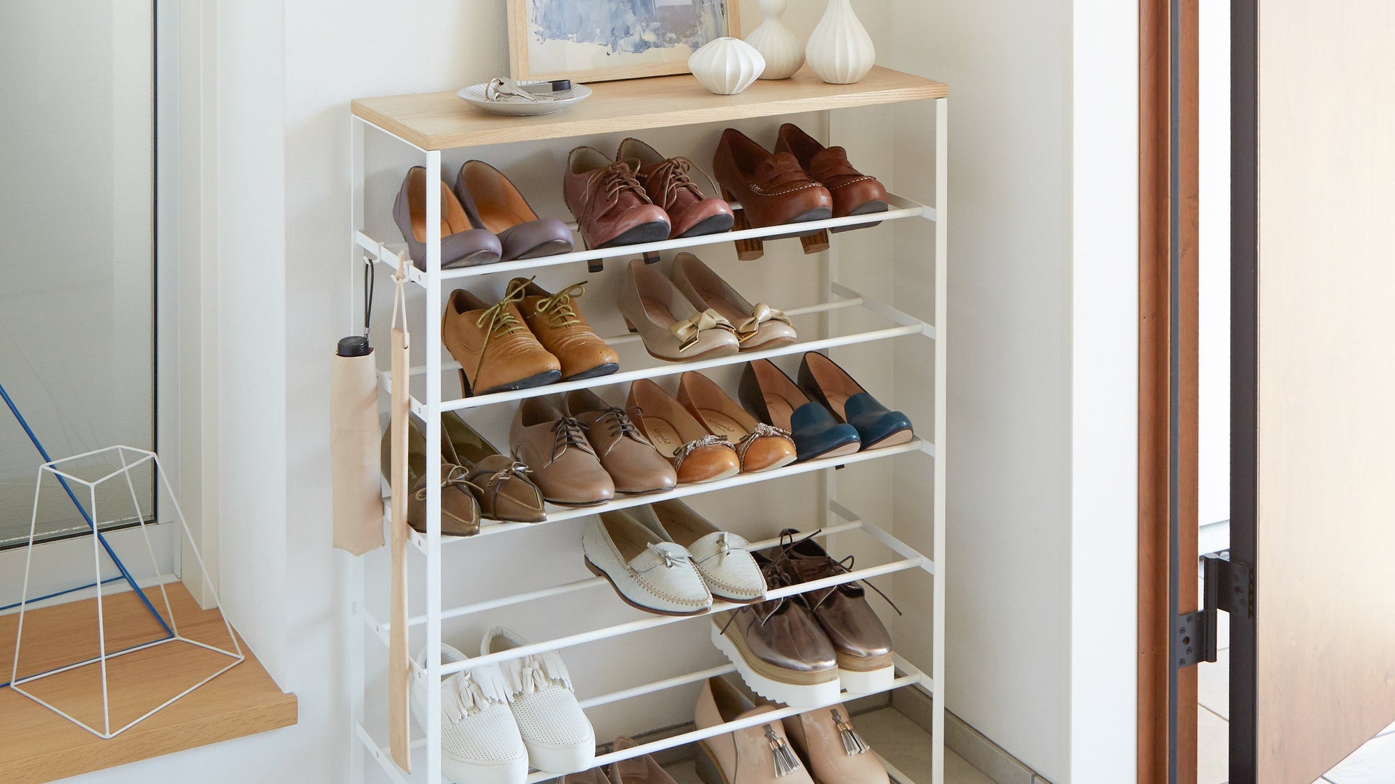 Six-Tier shoe rack with chic wood console from Yamazaki Home. Featured in the a minimalist entryway. Catch-all and art decorate the top shelf.  