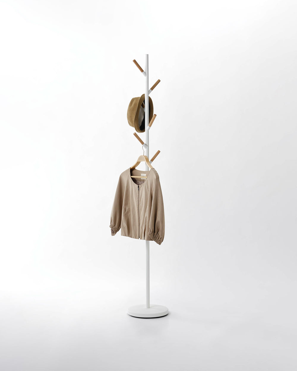 Yamazaki Home White Freestanding Coat Rack holding a hat and coat.