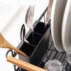 Removable utensil holder holding three forks on a black dish drying rack with wood handles in a modern kitchen.