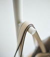 Close up of white Yamazaki Coat Rack arm with a purse strap hung on it