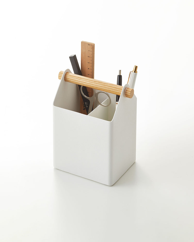Yamazaki Home white pen stand with a wood accent holding pens. 
