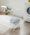 Full length view of Rolling Wire Basket holding clothes in laundry room by Yamazaki Home.