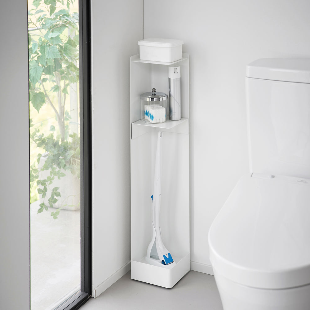 White Yamazaki Home Rolling Bathroom Organizer next to a toilet storing a toilet brush, cleaning spray and wet wipes