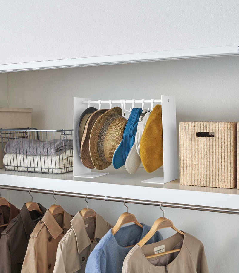 White Yamazaki Home hat rack hanging a variety of hats