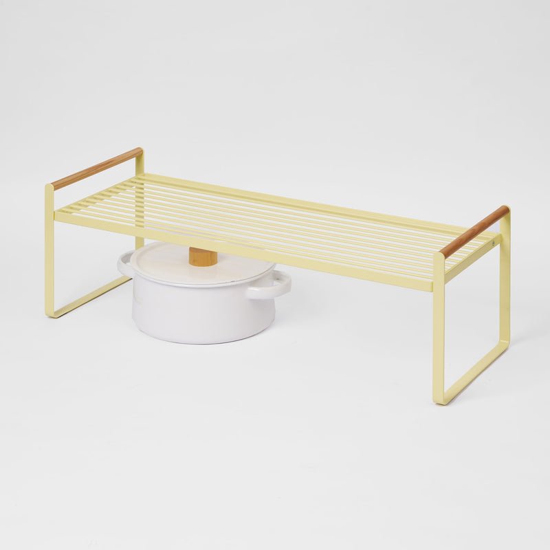 Yellow metal shelf with a white pot on a light gray background