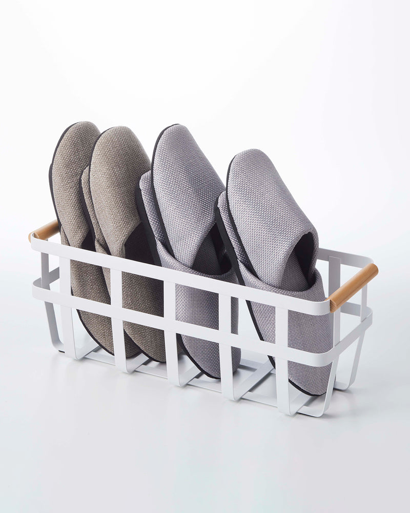 Narrow white storage basket by Yamazaki, holding slippers