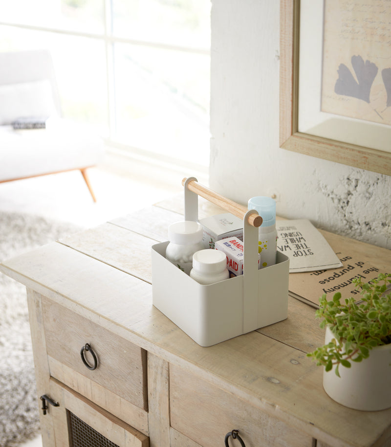 White Storage Caddy holding first-aid items on bureau countertop by Yamazaki Home.