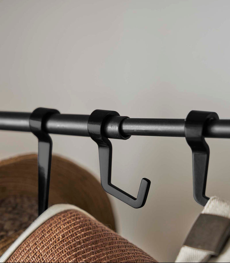 Close up of hooks on black Yamazaki Home hat rack hanging a variety of hats