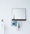 A black Yamazaki Magnetic Mirror With Storage Rack attached to a door holding bottles.