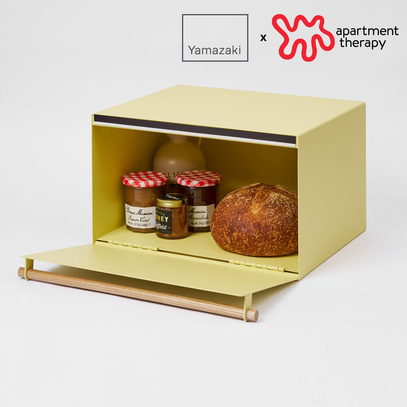 Bread Box with props on the white background, having a logo on the upper right.
