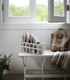 White Storage Basket containing slippers on bench by Yamazaki Home.