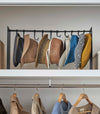 Frontal view of black Yamazaki Home hat rack hanging a variety of hats in a closet