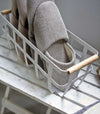 Close up view of white Storage Basket holding slippers by Yamazaki Home.