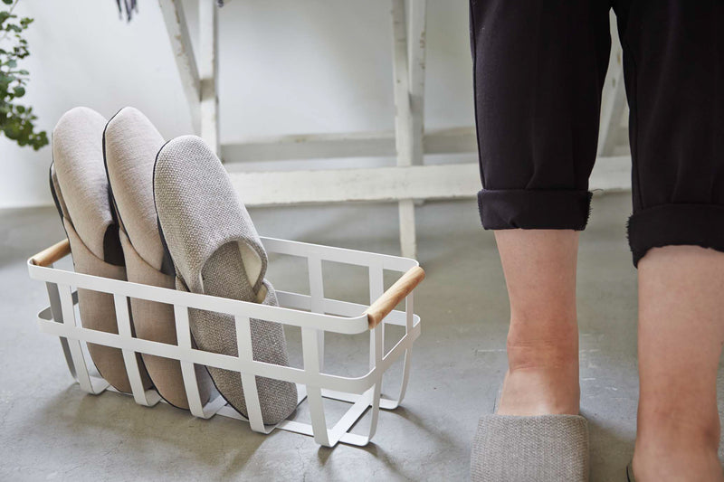 White storage basket holding slippers by Yamazaki Home.
