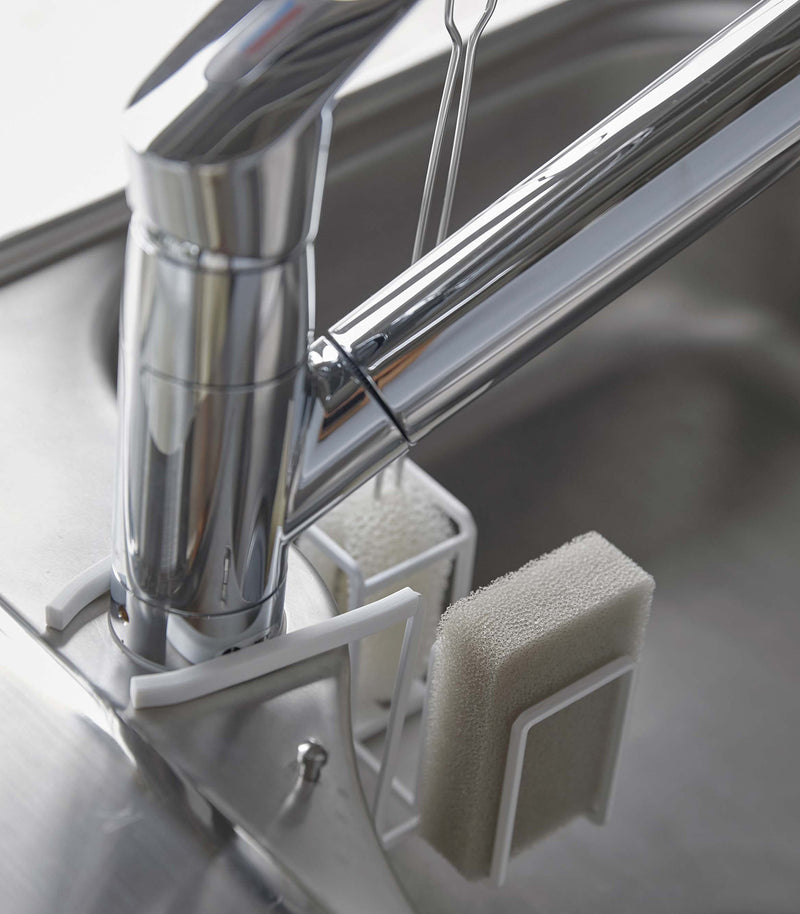 Rear of white Steel Yamazaki Home Faucet-Hanging Sponge & Brush Holder attached to a faucet