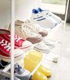 Close up side view of white Yamazaki Entryway Organizer with shoes on it