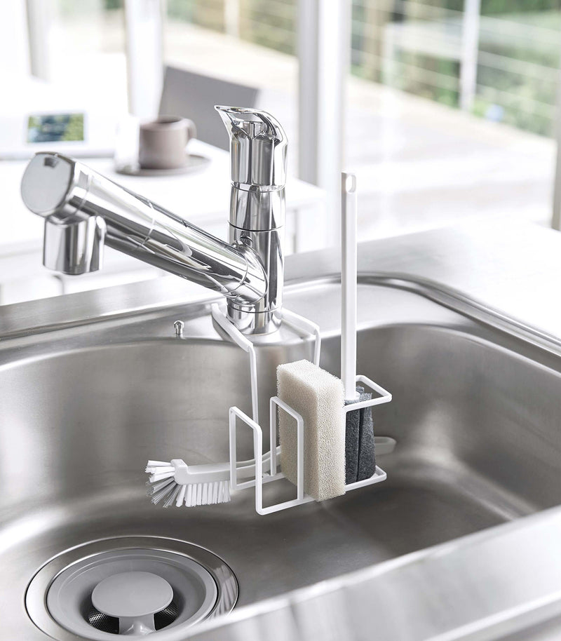White Steel Yamazaki Home Faucet-Hanging Sponge & Brush Holder holding a sponge and two brushes