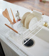 White Over-the-Sink Expandable Dish Drying Rack holding dishware in kitchen by Yamazaki Home.