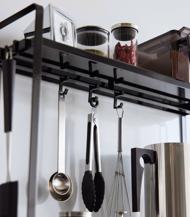 Hooks of Yamazaki Home Two-Tier Countertop Rack holding utensils.