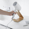 Someone placing a hair dryer on an ash Yamazaki Home Hair Dryer and Iron Stand