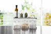 Front view of white Pantry Organizer holding spices and ingredients on upper shelf by Yamazaki Home.