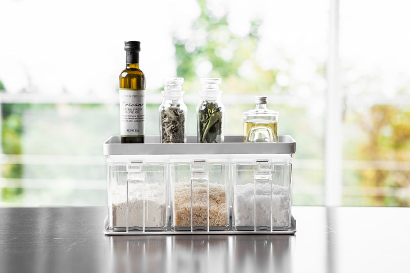 Front view of white Pantry Organizer holding spices and ingredients on upper shelf by Yamazaki Home.
