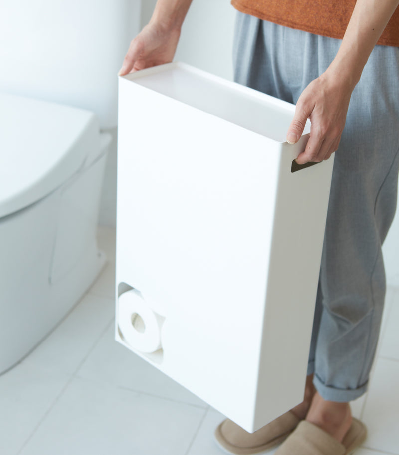 Front view of white Toilet Paper Stocker carried by handles in bathroom by Yamazaki Home.
