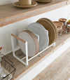 Wood-Accented Dish Storage Rack displaying plates on shelf by Yamazaki Home.