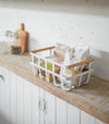 White storage basket holding food items on shelf by Yamazaki Home.