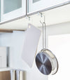White Undershelf Hangers holding pan and cutting board in kitchen by Yamazaki Home.
