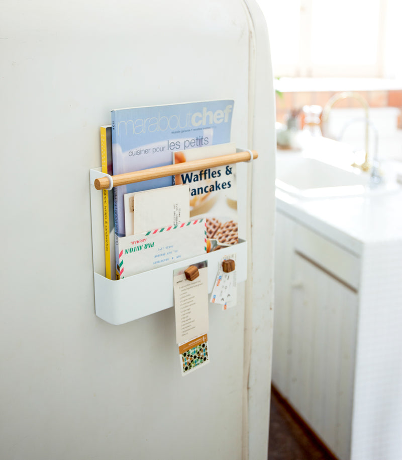 Side view of black Two-Tier Dish Rack holding dishware and cleaning accessories by Yamazaki Home.