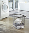 Black Wire Laundry Basket holding clothes in laundry room by Yamazaki Home.