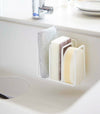 White Sponge Holder containing sponges in kitchen sink by Yamazaki Home.