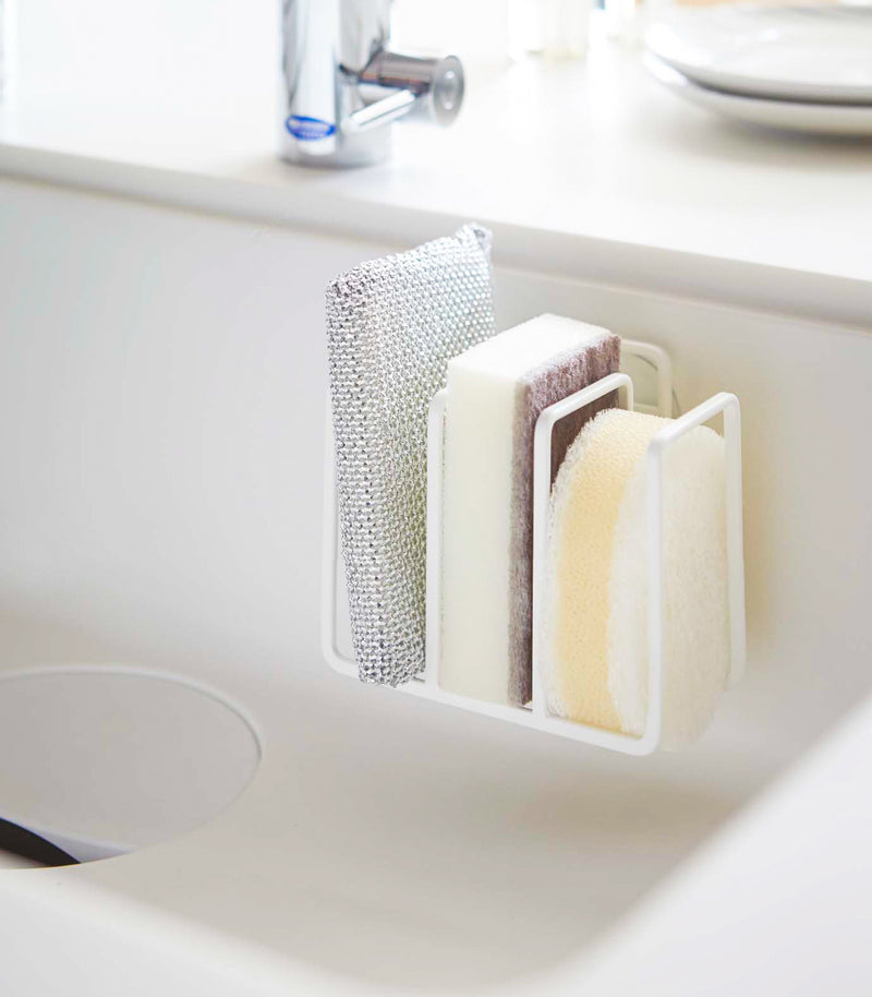 White Sponge Holder containing sponges in kitchen sink by Yamazaki Home.