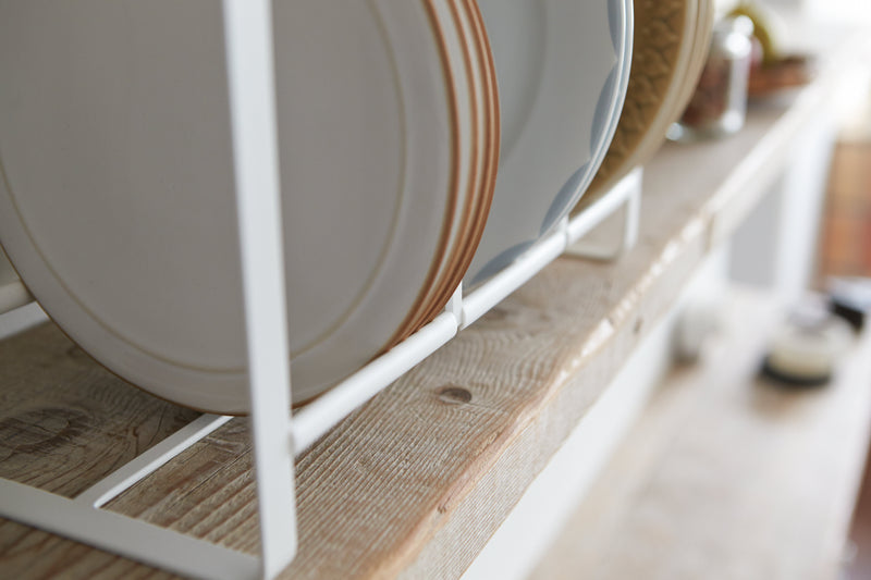 Close up bottom view of Wood-Accented Dish Storage Rack holding plates on shelf by Yamazaki Home.