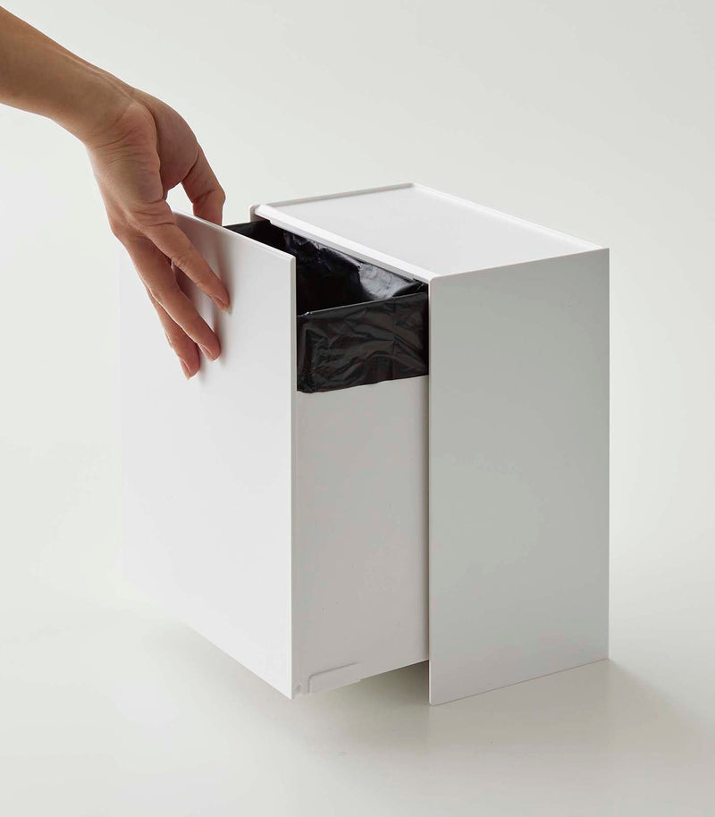 Person adjusting bin drawer on white Wall-Mount Storage on white background by Yamazaki Home.
