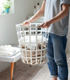 White Round Laundry Basket holding towels in laundry room by Yamazaki Home.