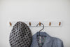 Front view of white Wall-Mounted Coat Hanger holding hat and jacket by Yamazaki Home.
