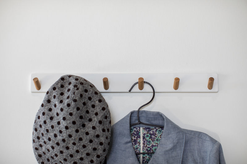 Front view of white Wall-Mounted Coat Hanger holding hat and jacket by Yamazaki Home.