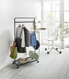 Black Rolling Coat Rack holding school uniform, backpack, hat, and school supplies by Yamazaki Home.