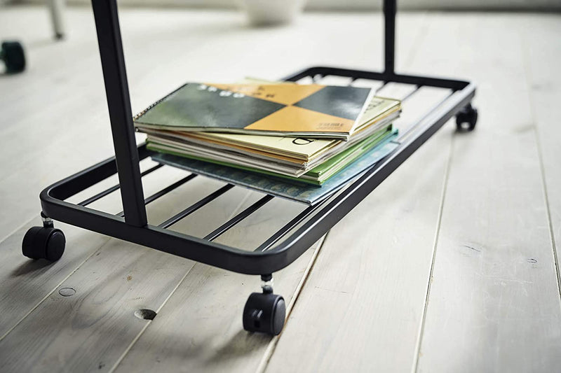 Bottom view of black Rolling Coat Rack holding books by Yamazaki Home.
