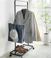 Black Rolling Coat Rack holding jackets, bag, hat, and shoes by Yamazaki Home.