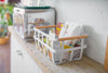 Side view of white Storage Basket holding snack food on shelf by Yamazaki Home.