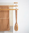 Front view of Bath Towel Rack holding towels and brush on white background by Yamazaki Home.