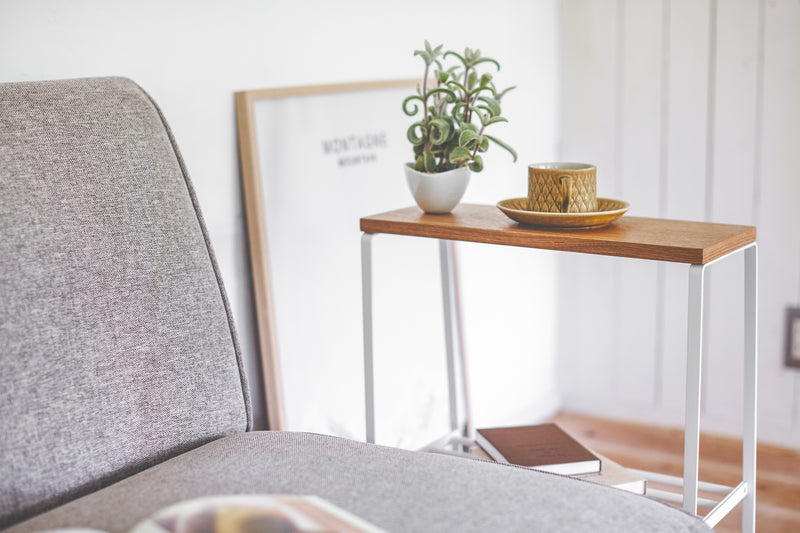 End Table holding cup, plant, and books in living room by Yamazaki Home.