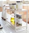 Side view of white Countertop Shelf on kitchen counter displaying spices and oil by Yamazaki Home.