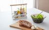 Front view of white Countertop Storage Caddy holding spices on kitchen table by Yamazaki Home.