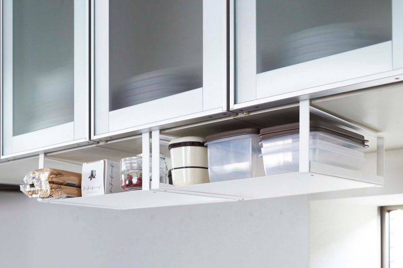 Side view of wooden handle on white Dish Rack  holding  washcloth by Yamazaki Home.